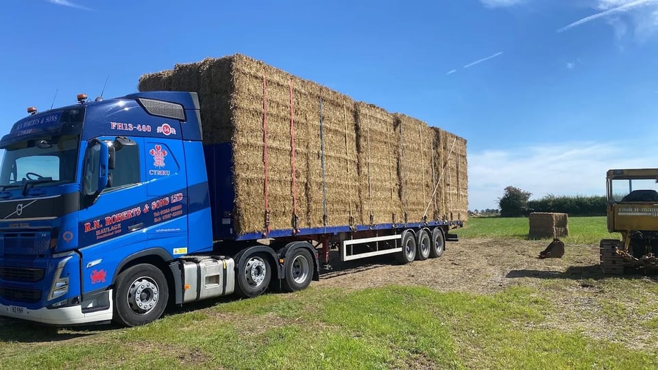RN Roberts flatbed trailer loaded with stacked agricultural bales